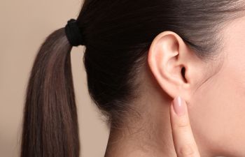 A woman pointing at her earlobe.