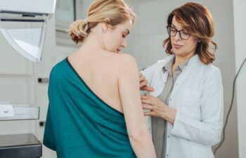 Woman gynecologist doing breast exam to her patient.